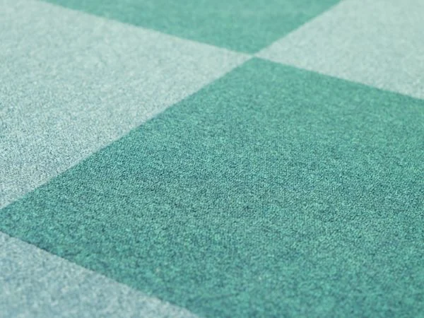 Close view of green modular carpet tiles laid in a geometric pattern