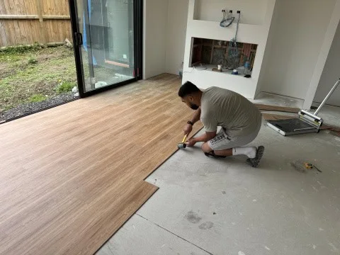 Flooring installer fitting wood-look SPC planks in an Auckland home